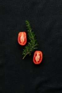 Kaboompics - Halved Tomatoes with Rosemary on a Black Background