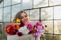 Kaboompics - Woman Smiling Behind Dahlia Bouquet In Sunlit Greenhouse