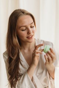 Kaboompics - Woman Holding a Small Green Moisturizer Jar in a Skincare Routine