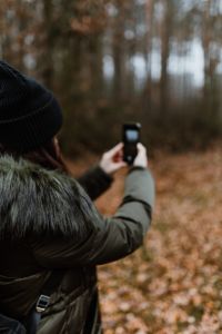 Kaboompics - A woman takes a picture with her iPhone X in the autumn forest