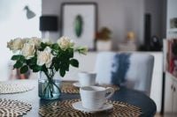 Kaboompics - Round breakfast table with golden coffee mats and white flowers