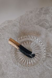 Kaboompics - Burning Palo Santo Stick on Crystal Incense Dish with Smoke, Marble Background