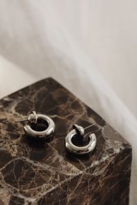 Kaboompics - Bold Silver Hoop Earrings on a Dark Marble Display Block
