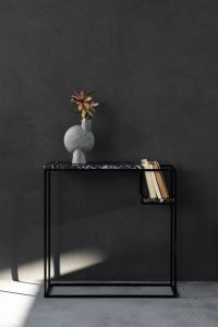 Kaboompics - Black Marble Console with Books and Sculptural Vase Against a Dark Wall