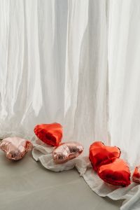 Kaboompics - Red and Blush Heart Foil Balloons on White Sheer Fabric with Copy Space