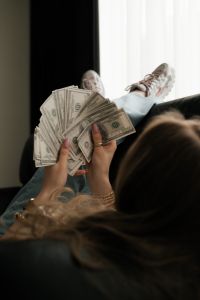 Kaboompics - Woman Holding a Fan of Cash While Lying on a Sofa