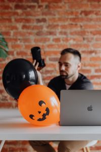 Kaboompics - Photographer Holding Camera Beside MacBook and Halloween Balloons