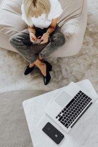 Kaboompics - Top-Down View of Woman Using Phone on Sofa with Laptop Below