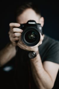 Photographer at Work: Man Using a DSLR Camera to Capture a Pink Rose Display