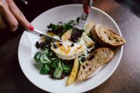 Kaboompics - Hands Cutting Warm Goat Cheese Salad with Pear, Greens, Dried Fruit and Toasted Bread