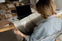 Kaboompics - Designer Browsing Interior Design Catalog at Material Sample Desk