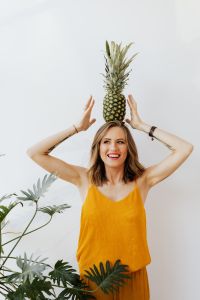 Kaboompics - Pineapple Balanced on Head as Woman Raises Her Hands, Minimal White Background