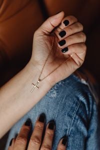 Kaboompics - Close-Up of a Hand Gripping a Gold Cross Necklace