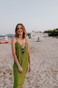 A woman in a green dress on the beach with white sunglasses