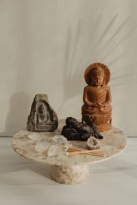 Kaboompics - Wooden Buddha And Stone Statue With Amethyst, Rose Quartz, Crystals, and Matchsticks On Marble Table