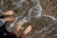 Kaboompics - Top View of Bare Feet in Foamy Sea Water on Rocky Pebble Beach