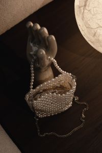Kaboompics - Pearl Beaded Handbag on a Sculptural Display Hand Against Dark Wood