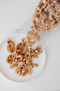 Kaboompics - Soft-Focus Walnuts Spilling from a Glass Container on a White Kitchen Counter