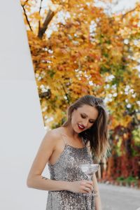 Kaboompics - Woman Looking Down at Champagne Flute among Autumn Leaves