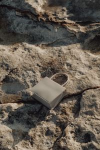 Kaboompics - Small White Handbag with a Long Strap on Coastal Stone