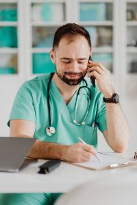 Kaboompics - Doctor on Phone While Completing Paperwork