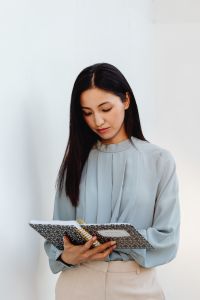 Kaboompics - Asian Woman Using a Pink Laptop Against a White Background