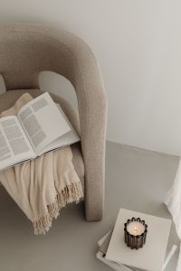 Kaboompics - Beige Armchair with Open Book, Fringed Throw and Candle