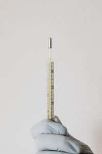 Kaboompics - Vertical Glass Fever Thermometer Held by Gloved Hand, Minimal Medical Background