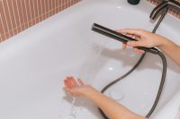 Kaboompics - Hand Holding Black Shower Head Over White Bathtub