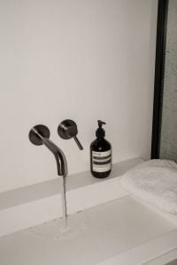 Kaboompics - Minimal Bathroom Sink with Running Faucet and Black Soap Bottle