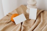 Kaboompics - Orange Fruit and Two Blank Business Cards with a Sculptural Vase on Beige Linen