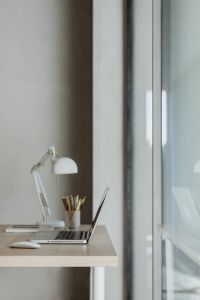 Kaboompics - Work from Home Desk with Open Laptop, White Lamp and Pencil Holder by a Bright Window