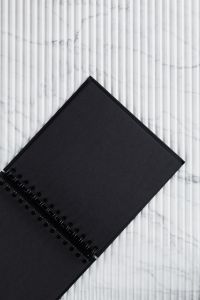 Kaboompics - Top View of Blank Black Spiral Notebook on White Veined Marble, Minimalist Flat Lay
