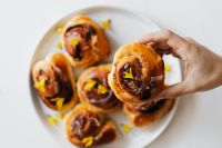 Kaboompics - Overhead Cinnamon Roll Plate with a Handheld Iced Bun for Baking Content
