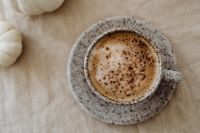Kaboompics - Close-Up Cappuccino in a Speckled Ceramic Cup beside a White Pumpkin on Beige Linen