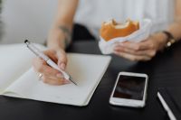 Kaboompics - Woman Writing in Notebook While Eating Lunch