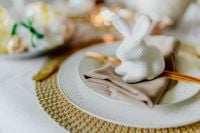 Kaboompics - White Ceramic Bunny on a Dinner Plate with Wooden Cutlery and Woven Gold Charger