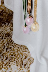 Kaboompics - Hanging Pink and Gold Easter Egg Ornaments on Green and Gold Ribbons over White Linen