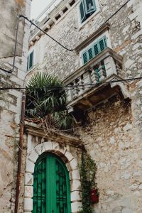 Kaboompics - Green Arched Door beneath an Ornate Stone Balcony in Rovinj