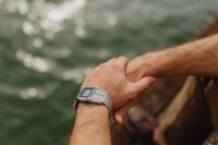 Kaboompics - Close-Up of Clasped Hands with a Silver Calculator Watch over Sparkling Water