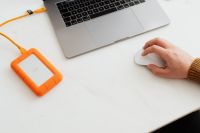 Kaboompics - Man works on a computer at his desk, mobile phone, portable hard drive