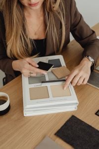 Kaboompics - Woman Comparing Neutral Material Samples in Catalog Beside Coffee