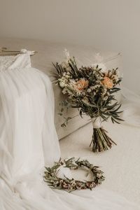 Kaboompics - Wedding Dress and Bouquet Draped Over a Neutral Chair