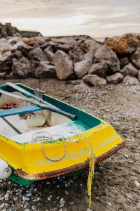 Kaboompics - Empty Yellow and Green Dinghy on a Pebble Beach