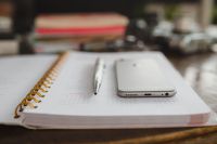 Kaboompics - Soft-Focus Planner, Smartphone and Silver Pen with Stacked Notebooks on Desk