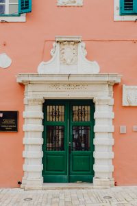 Kaboompics - Ornate Green Door and White Stone Portal on a Pink Rovinj Facade
