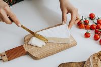 Kaboompics - Woman Cutting a Block of Cheese