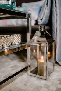 Kaboompics - Silver Lantern and Glass Candle Holders beside Blue Sofa Cushions, Vertical Living Room Decor