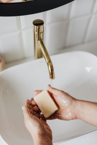 Kaboompics - Vertical View of Hands Holding Bar Soap beneath a Brass Bathroom Faucet, Hygiene Campaign
