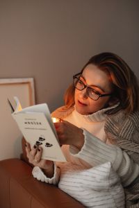 Kaboompics - Woman Reading by Candlelight in a White Knit Sweater